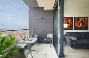 Un balcón moderno con una mesa de comedor, sillas, un sofá y dos cuadros.