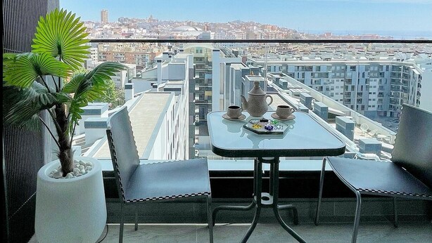 A balcony with a table, chairs, and a potted plant. - Unik Vacation The Tower (Tarragona)