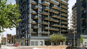 A modern high-rise building with multiple balconies, a pedestrian walkway, and a crosswalk in front. - Unik Vacation The Tower (Tarragona)