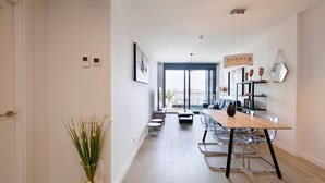 A modern living room with a dining area, a lounge sign, and a large window providing a view. - Unik Vacation The Tower (Tarragona)