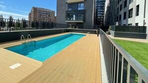A rooftop pool area with a wooden deck and a clear blue pool. - Unik Vacation The Tower (Tarragona)