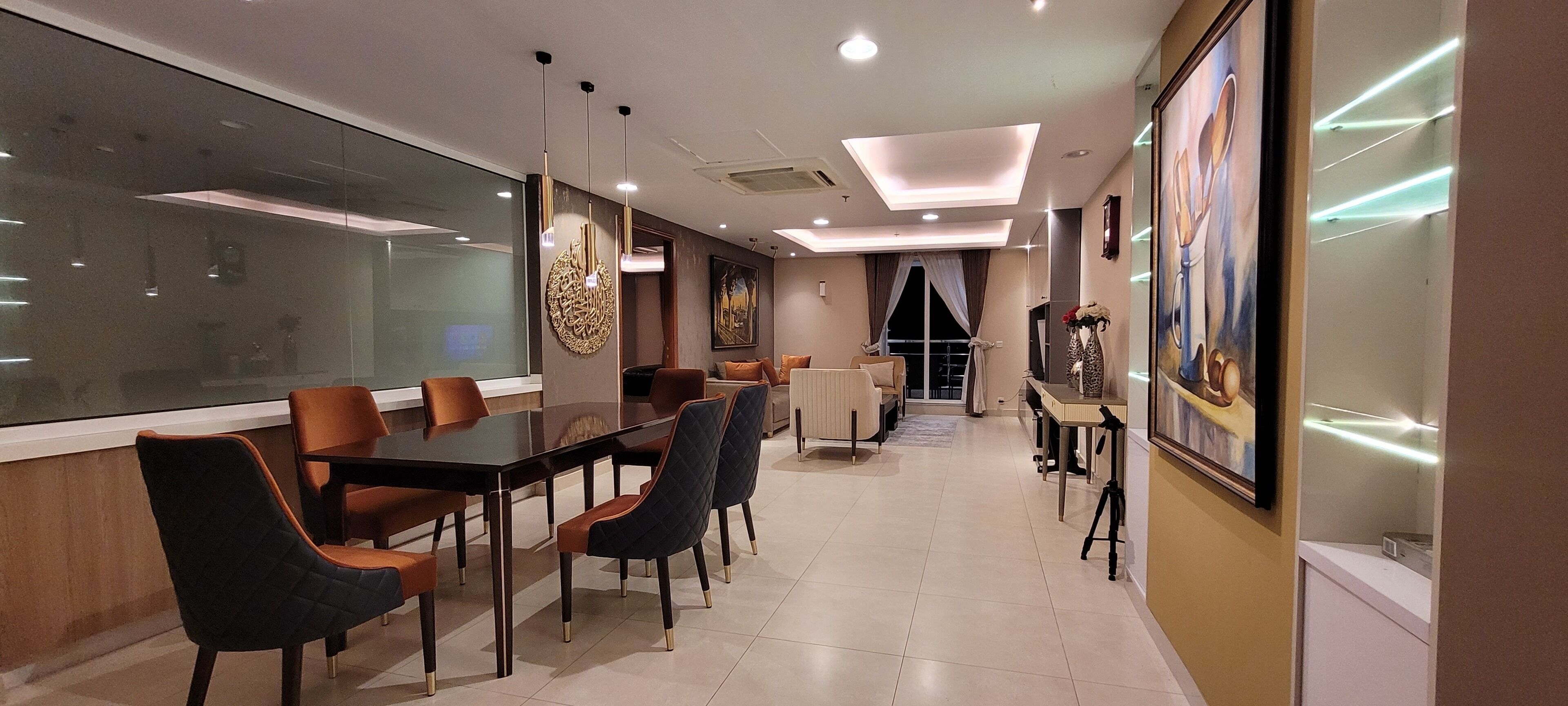 A modern conference room with a glass table, leather chairs, recessed lighting, and artwork on the walls.
