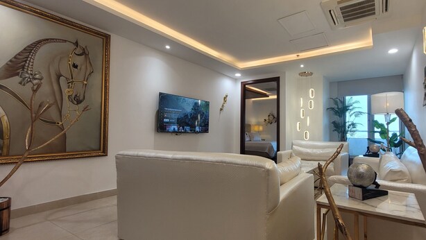 Una sala de estar moderna con un cuadro grande de un caballo enmarco, un televisor de pantalla plana y una lámpara decorativa.