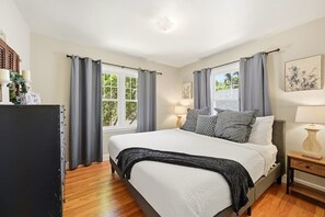 A bedroom with a bed, curtains, a bedside table, and a window.
