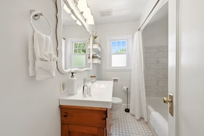 A bathroom with a white vanity, a mirror, a towel rack, a toilet, and a shower area.