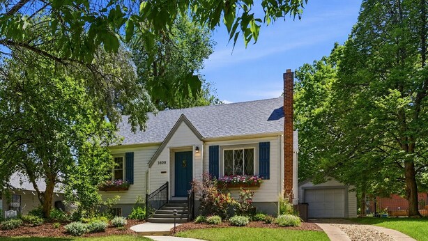 A single-story house with a front porch, a chimney, and a well-maintained lawn. - Charming Historic Cottage • Cozy Family Getaway! (Greeley)