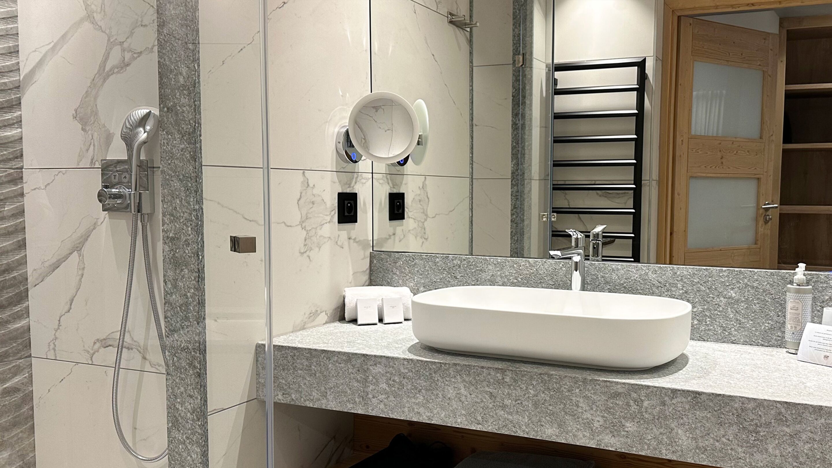 Ein modernes Badezimmer mit Marmorwaschtisch, integriertem Waschbecken, Duschbrause und Handtuchhalter.