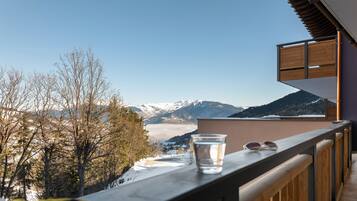 A balcony with a clear view of snow-covered mountains and a glass of water.
