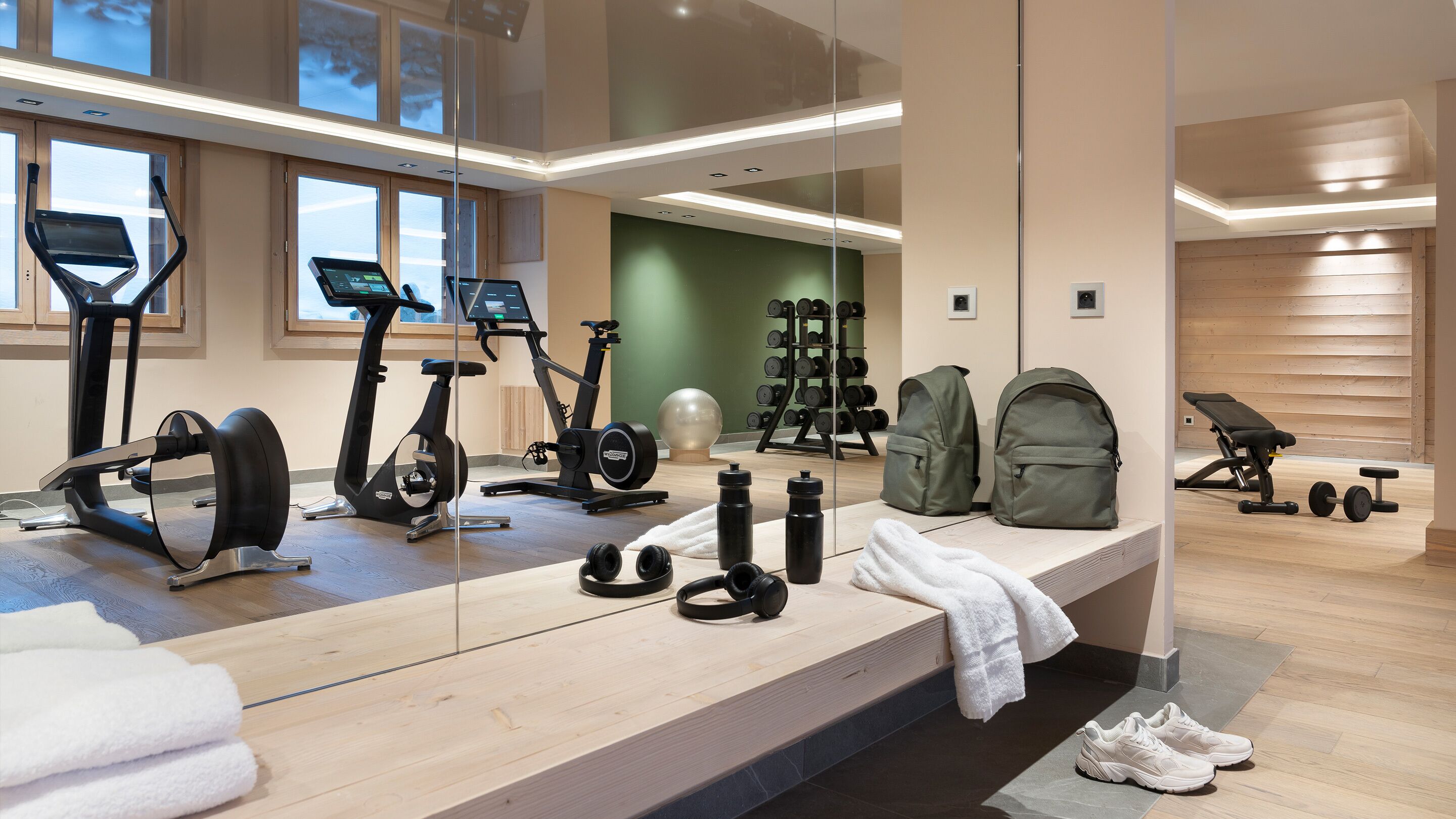 A modern gym with exercise equipment, a mirror, and a bench.