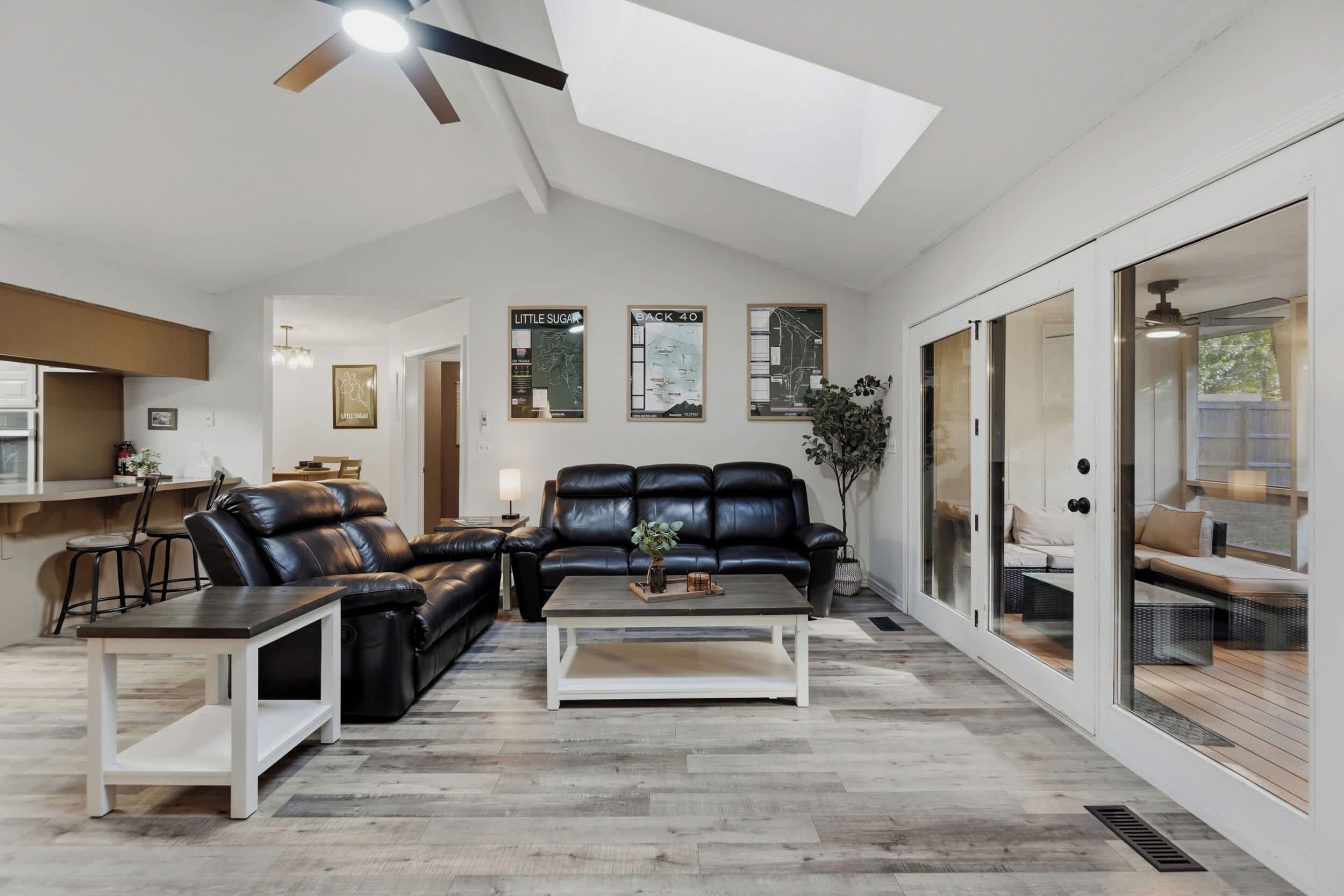 A spacious living room with a black leather sofa, a coffee table, and a dining area with a bar.