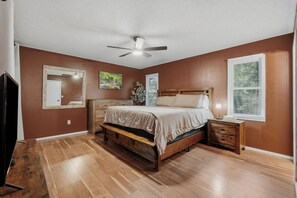 A bedroom with a wooden bed, a nightstand, a mirror, and a ceiling fan.