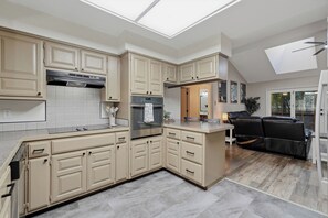 A modern kitchen with a skylight, built-in appliances, and a dining area with a leather sofa. - Bike In/Bike Out Home in Bella Vista (Bella Vista)