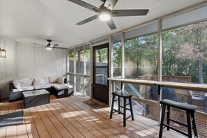 A covered outdoor seating area with a ceiling fan, a sofa, and a table. - Bike In/Bike Out Home in Bella Vista (Bella Vista)