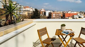 A rooftop terrace with two wooden chairs and a table, featuring a pineapple and a magazine. - Sant Pau Patio 2BR Near Avinguda Gaud With Patio (Barcelona)