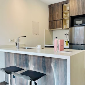 A modern kitchen with a stainless steel refrigerator, a built-in microwave, and a wooden cabinet above the counter. - w Sunny 2BR in Modern Building in Chico (Bogotá)