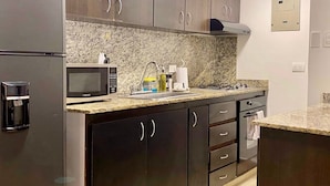 A modern kitchen with dark cabinets, a stainless steel refrigerator, a microwave, and a gas stove. - w Fantastic 2BR Apartment w AC in Cartagena (Cartagena)