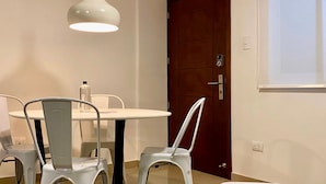 A dining area with a white table and chairs, a hanging pendant light, and a wooden door. - w Fantastic 2BR Apartment w AC in Cartagena (Cartagena)