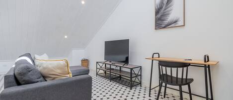 A modern living room with a sofa, a TV, a desk, and a chair.