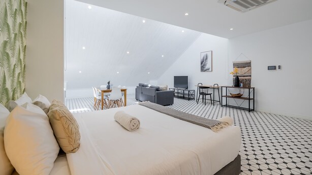 Una stanza moderna e luminosa con un letto grande, una scrivania e un divano.