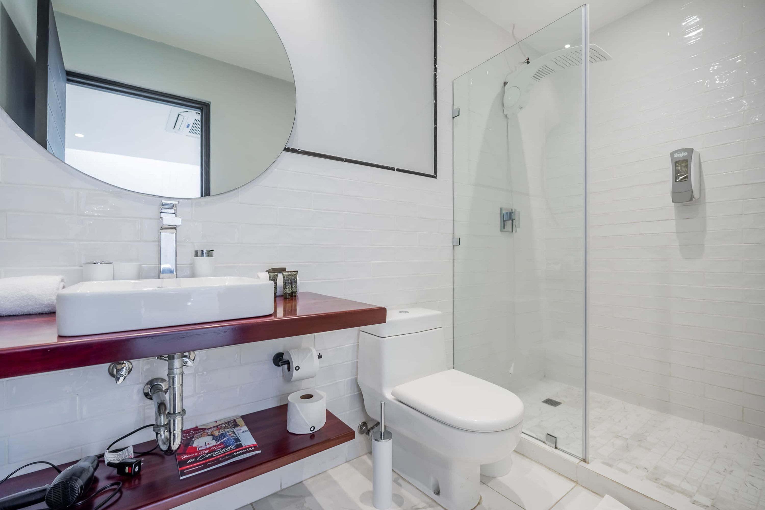 A modern bathroom with a white sink, toilet, and glass shower enclosure.