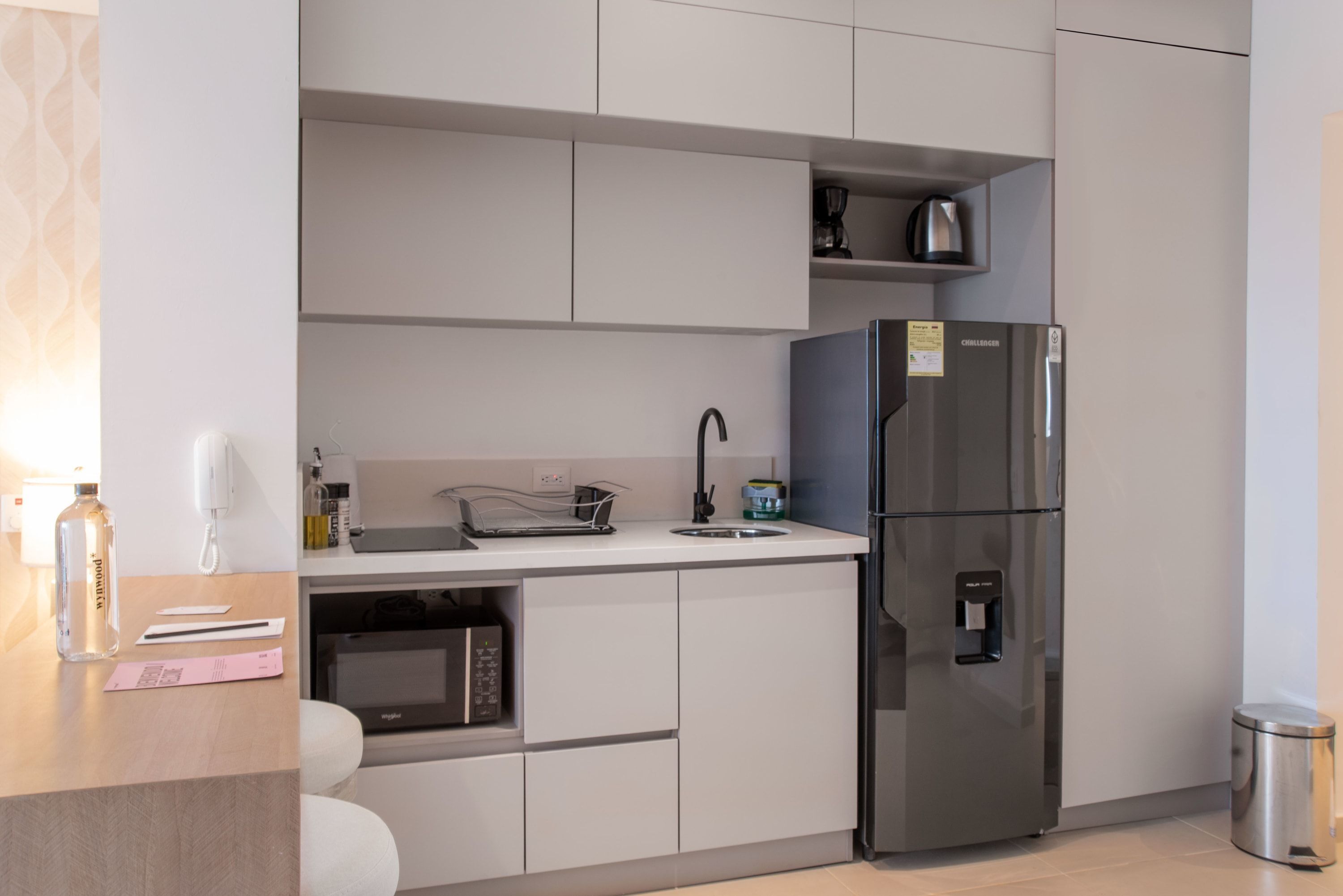 A modern kitchen with a built-in microwave, a stainless steel refrigerator, and a coffee maker on the countertop.