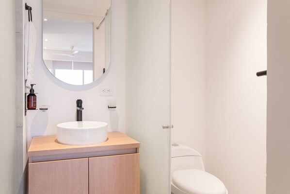 A modern bathroom with a round mirror, a white sink, and a toilet. - w Comfortable Loft w Balcony in Crespo (Cartagena)