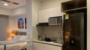 A modern kitchen with a refrigerator, microwave, and sink. There is a dining area with a table and chairs. - w Marvelous Loft With Balcony in Crespo (Cartagena)