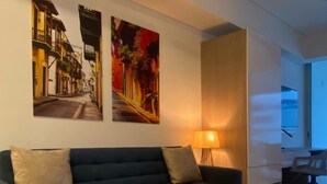 A modern living room with a dark sofa, a round wooden coffee table, and two vibrant street art pieces on the wall. - w Marvelous Loft With Balcony in Crespo (Cartagena)