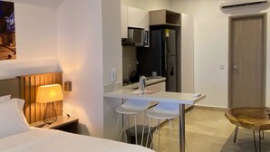 A hotel room with a bed, bedside lamp, desk, two chairs, a small table, and a ceiling fan. - w Marvelous Loft With Balcony in Crespo (Cartagena)