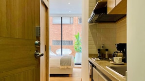 A modern kitchen with a wooden door, a coffee machine, and a view of a brick building outside. - w Phenomenal Loft With Modern Deco in Bogota (Bogotá)