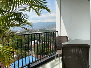 A balcony with a view of a cityscape, a pool, and a palm tree. - w Breathtaking 1BR With Terrace at Poblado (Medellín)