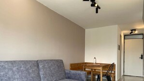 Una sala moderna con un sofá gris, una mesa de comedor de madera y una puerta al fondo.