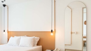 Ein Schlafzimmer mit Bett, Nachttisch mit Telefon und einem großen Spiegel.