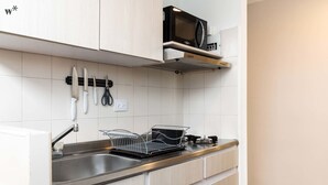 Eine moderne Küche mit Spüle aus Edelstahl, Geschirrgestell und Mikrowelle auf einem Regal.