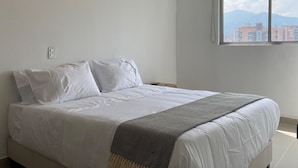 A bedroom with a bed, a window with a view of buildings, and a power outlet on the wall. - w Magnificent 1BR With Terrace at Poblado (Medellín)