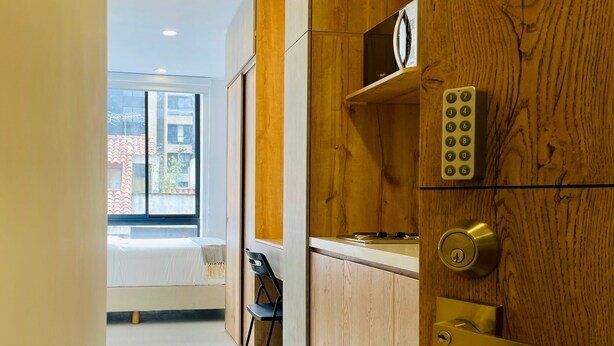 A modern kitchen with wooden cabinetry, a built-in microwave, and a keypad lock. - Majestic Loft in Santa Barbara (Bogotá)