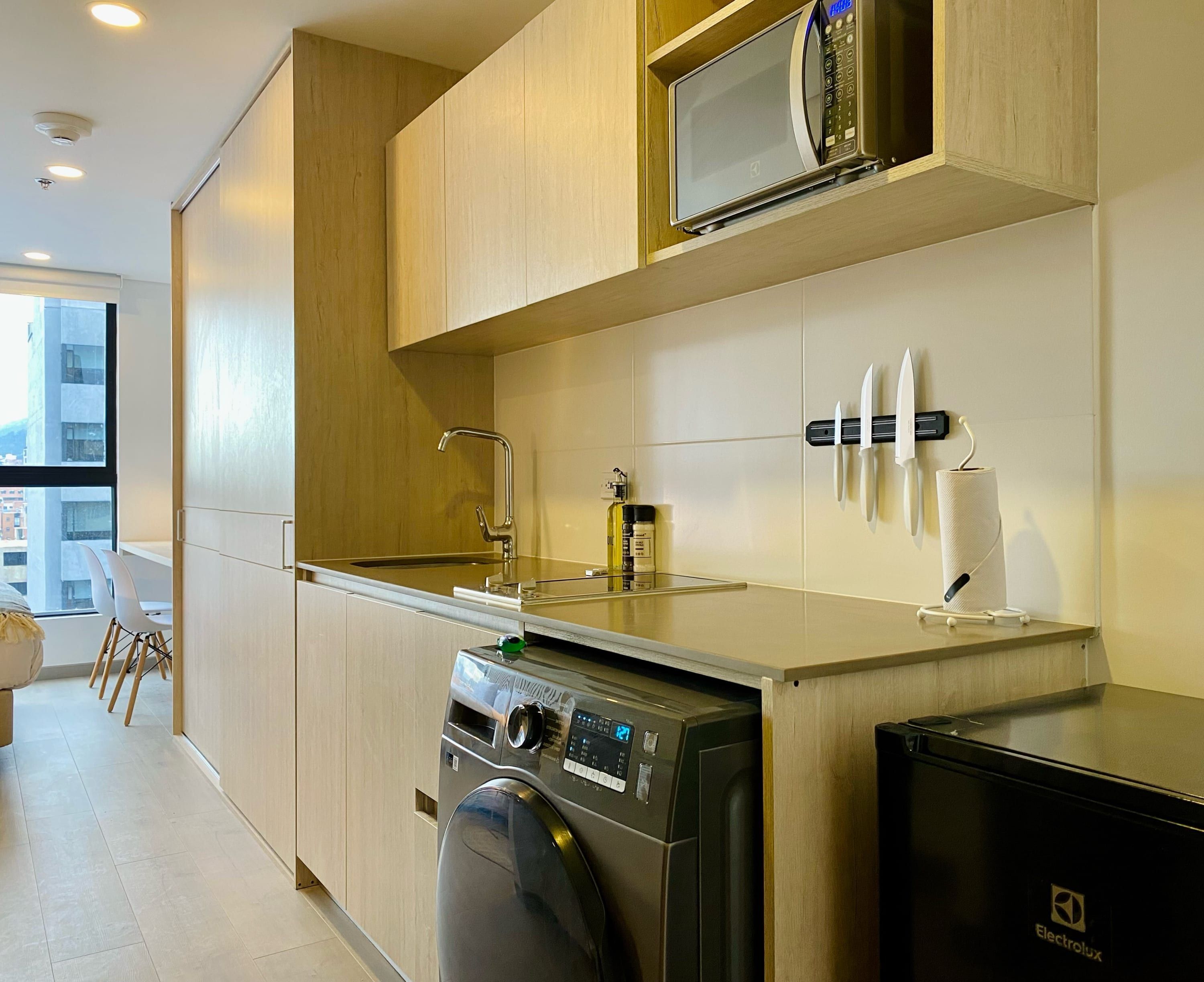 Une cuisine moderne équipée d’un lave-linge intégré, d’un four à micro-ondes et d’un porte-couteaux.