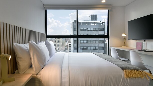 Une chambre d’hôtel moderne avec un grand lit, un bureau et une télévision.