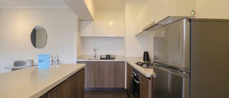 A modern kitchen with a stainless steel refrigerator, wooden cabinets, and a white countertop.
