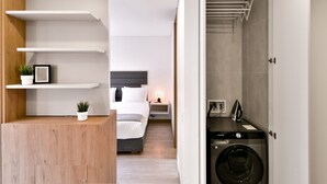 A modern hotel room with a bed, bedside table, and a built-in washer and dryer. - Lovely Loft With Modern Deco in Chapinero (Bogotá)