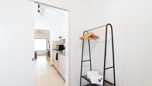 Ett modernt kök med vita skåp, en svart bänkskiva och en hängande hylla med handdukar.