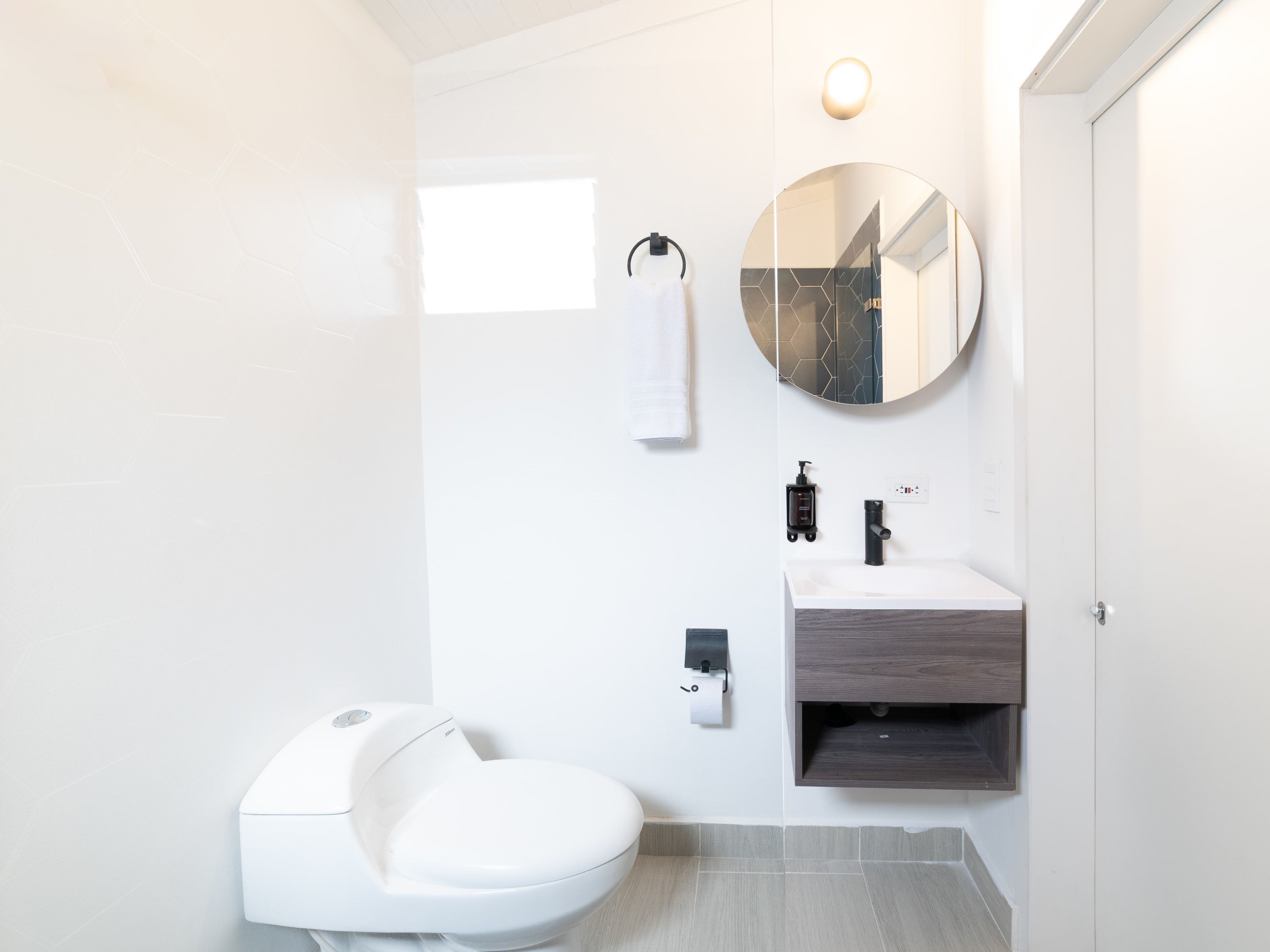 Un baño moderno con inodoro, lavamanos y espejo.