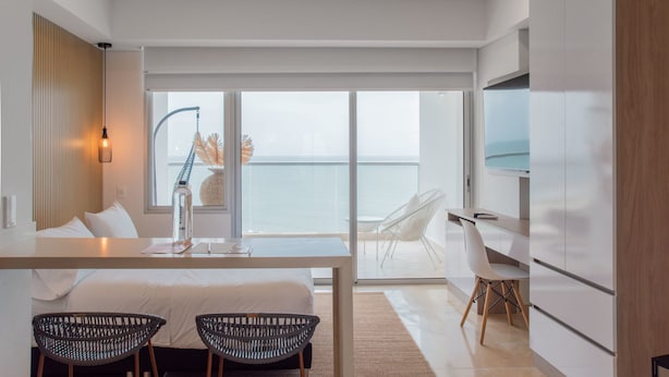 Een moderne hotelkamer met balkon, eethoek en keuken.