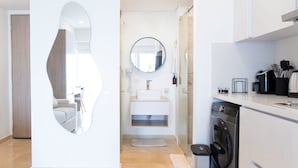 Een moderne badkamer met een grote spiegel, een wastafel en een wasmachine.