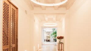 Un pasillo con una puerta de madera, una planta en maceta y un jarrón con flores.