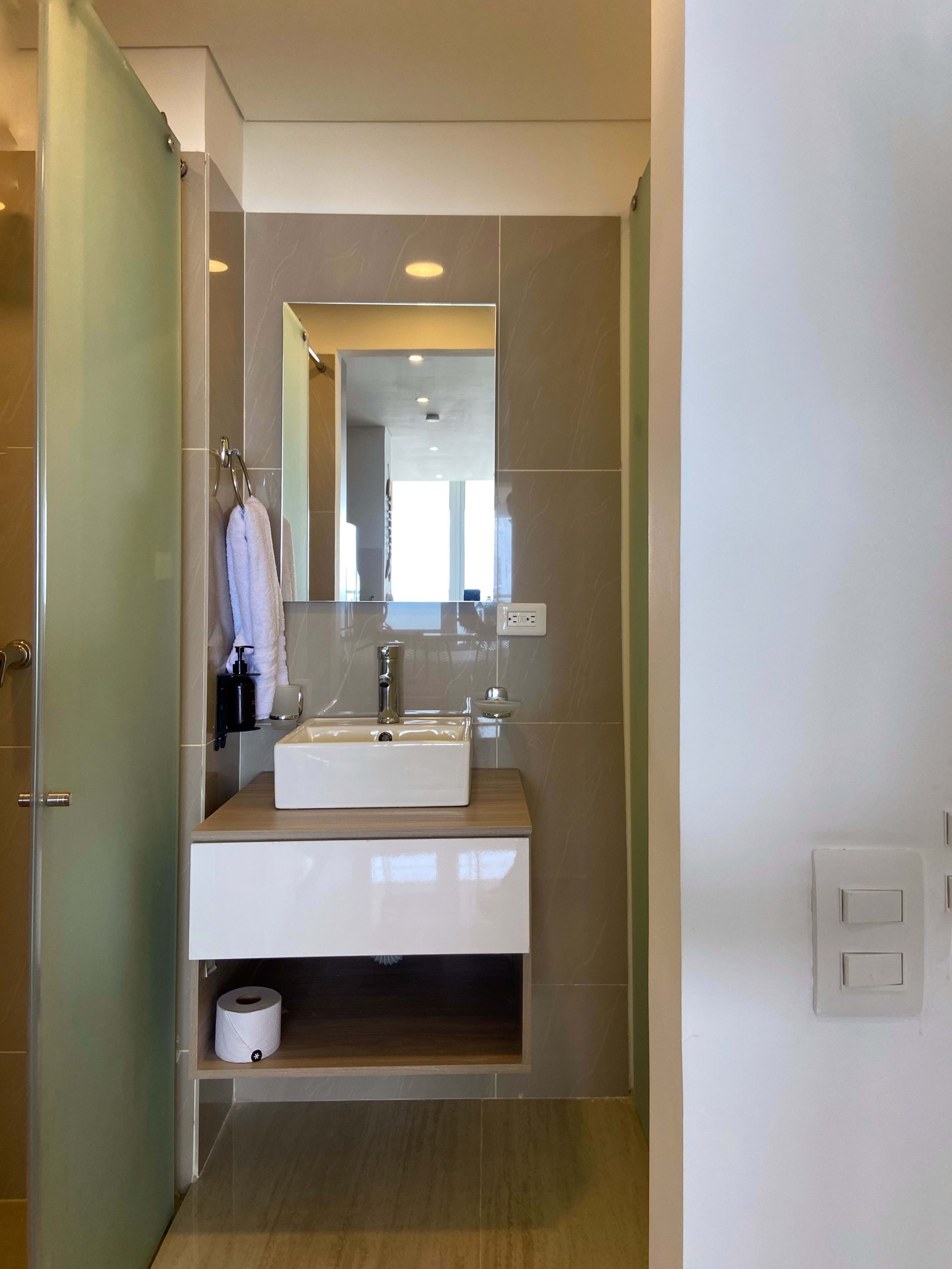 A modern bathroom with a large mirror, a sink, and a toilet.