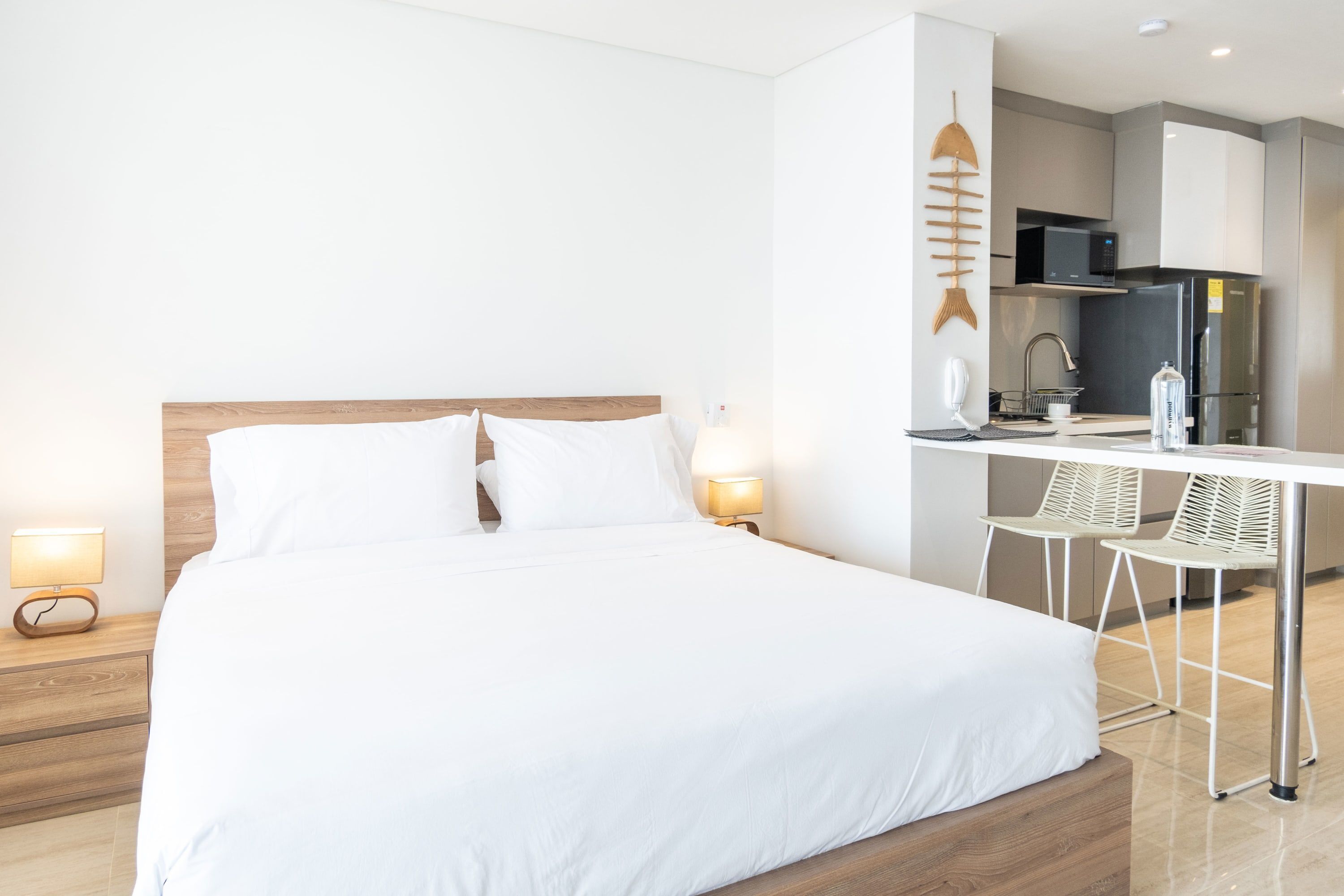 Et moderne hotelværelse med en stor seng, et skrivebord, en mikroovn og et køleskab.