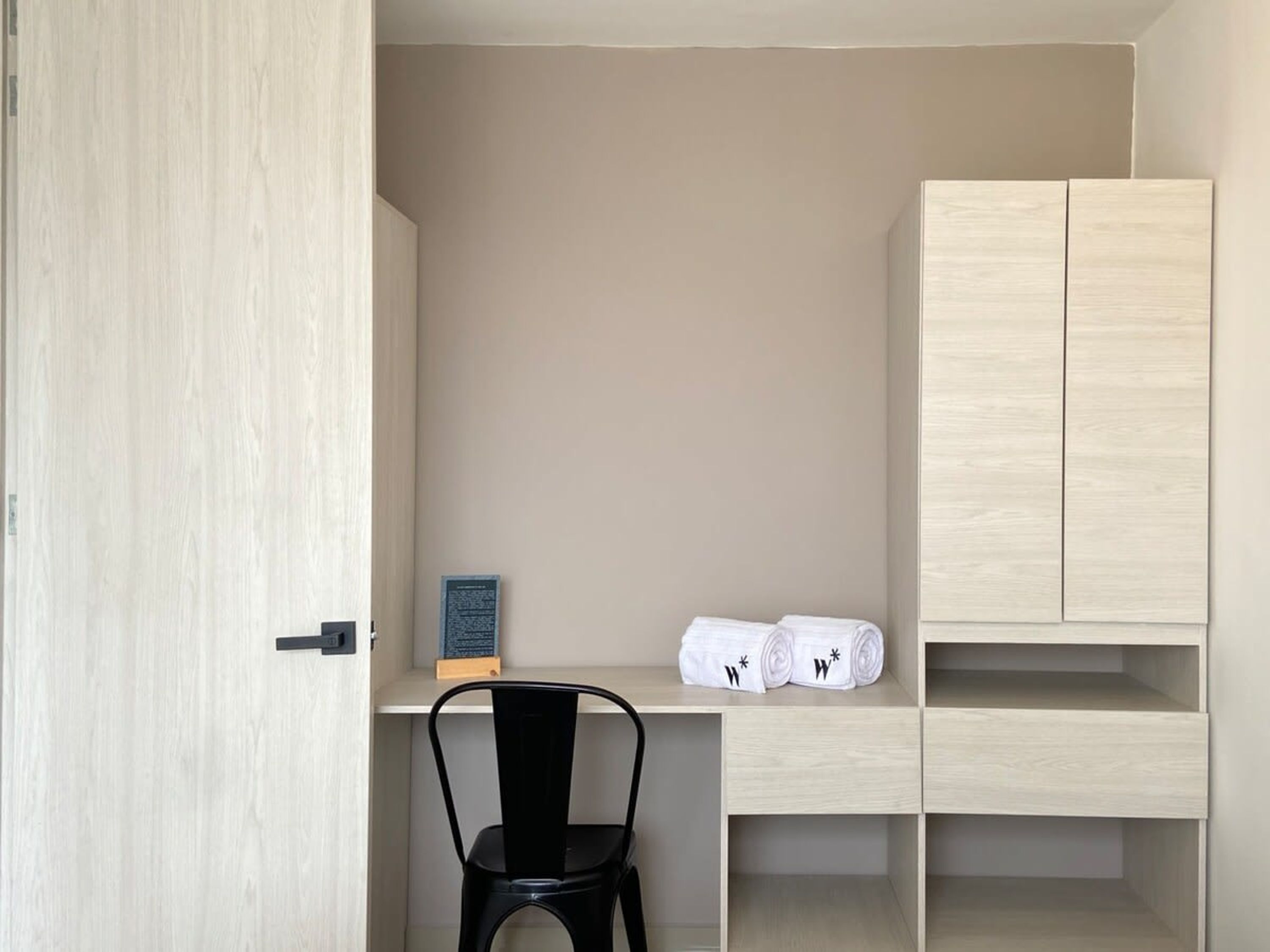 Una habitación pequeña y ordenada, con escritorio, silla y armario.