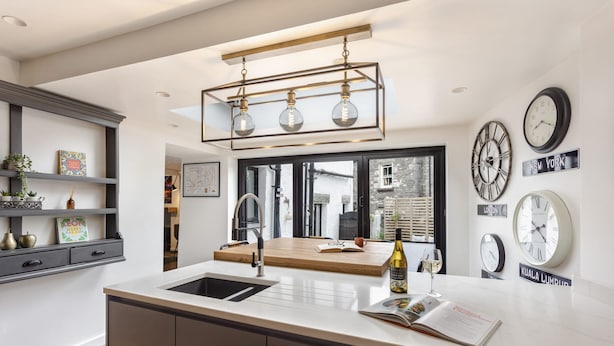 A modern kitchen with a central island, a built-in sink, and a hanging light fixture.