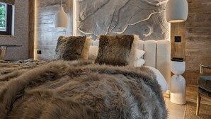 Een moderne slaapkamer met een groot bed, houten wanden en een wand met een steenachtige textuur achter het bed.